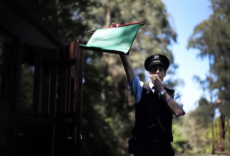 Puffing Billy railway guard Dom Franssen blows a whistle and holds up a flag signalling a train to depart Lakeside station near Melbourne, October 20, 2014. REUTERS/Jason Reed