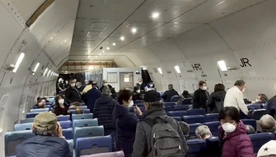 In this image from a video taken on Monday, Feb. 17, 2020, U.S. passengers who evacuated off the quarantined cruise ship the Diamond Princess, board a Kalitta Air plane bound for the U.S., at Haneda airport in Tokyo.(Cheryl and Paul Molesky via AP)