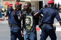 Police officers detain a demonstrator during a protest in Dakar