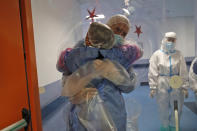 Ela Gubbiotti hugs her partner Giancarlo Vannimartini, an anesthesiologist who has been hospitalized for 10 days, in a safe room where patients and relatives can hug each other protected by a plastic film screen set up inside the COVID-19 ward of the Ospedale dei Castelli Hospital in Ariccia, near Rome, Wednesday, Jan. 20, 2021. (AP Photo/Alessandra Tarantino)