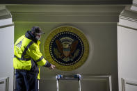 <p>An Architect of the Capitol worker places the Presidential seal on a wall ahead of the inauguration. </p>