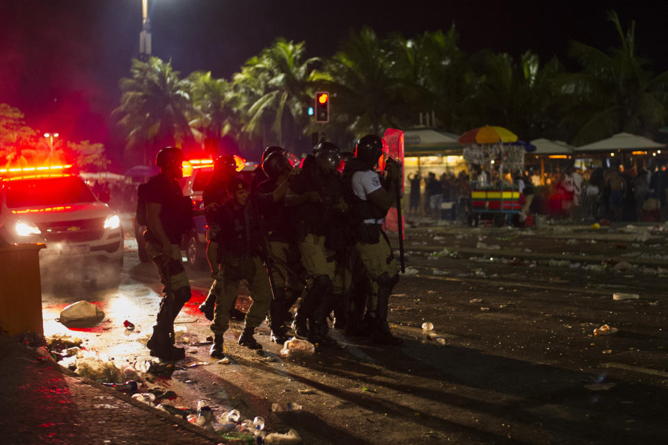 Police officers take position during clashes with party-goers after the official start of Carnival, on Copacabana beach, Rio de Janeiro, Brazil, Sunday, Jan. 12, 2020. Police officers and municipal guards dispersed attendees with gas bombs, and moments of tension were experienced in the deconcentration of the event, which brought together hundreds of thousands of people. (AP Photo/Bruna Prado)