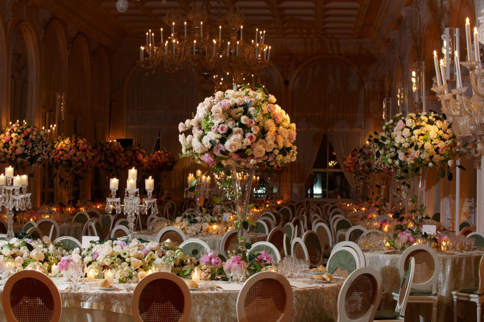 large hall decorated with long tables, large floral center pieces and tons of candles