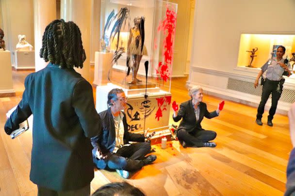 PHOTO: Declare Emergency protesters sit on the floor after smearing paint on the case and pedestal of Edgar Degas's 'Little Dancer Aged Fourteen' sculpture in the National Gallery of Art in Washington, Apr, 27, 2023. (AFP via Getty Images)