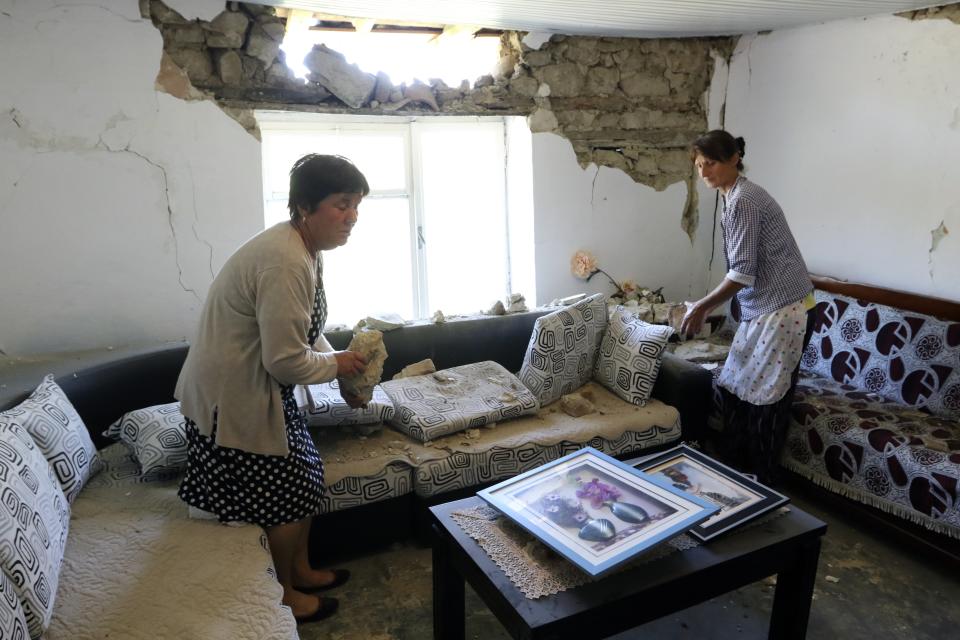 Two women clean up debris from a damaged house after an earthquake in Zhurje village, north of Tirana on Sunday, Sept. 22, 2019. Many residents in Albania's capital of Tirana and the port city of Durres have not gone back to their homes after a 5.8 magnitude earthquake injured 105 people and damaged hundreds of buildings. (AP Photo/Hektor Pustina)