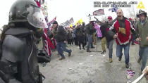 This still frame from Metropolitan Police Department body worn camera video shows Thomas Webster, in red jacket, at a barricade line at on the west front of the U.S. Capitol on Jan. 6, 2021, in Washington. Webster, a Marine Corps veteran and retired New York City Police Department Officer, is accused of assaulting an MPD officer with a flagpole. A number of law enforcement officers were assaulted while attempting to prevent rioters from entering the U.S. Capitol. (Metropolitan Police Department via AP)