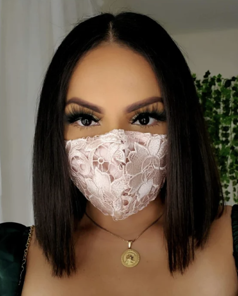 woman with black hair wearing light pink Lace Face Mask and gold necklace