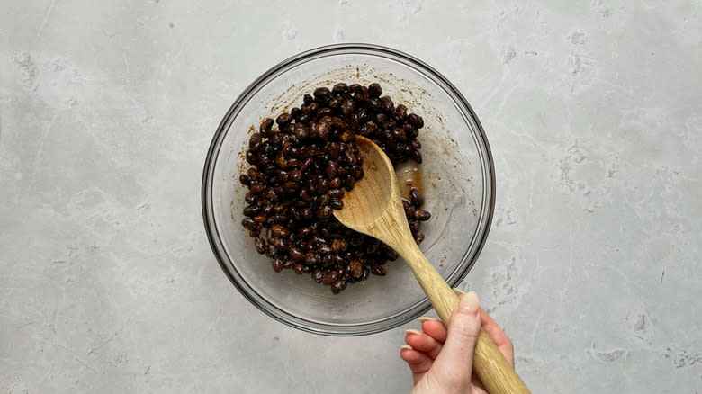 stirring black beans in bowl