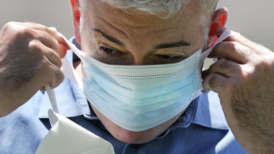 Brendan Williams, president of the New Hampshire Health Care Association, stretches the thin cloth band of a surgical mask, which was received in a shipment from the federal government, outside Webster at Rye senior care center on Wednesday, July 1, 2020, in Rye, N.H. The surgical masks which break when stretched, child-sized examination gloves and isolation gowns with no sleeve openings for hands make up the bulk of the personal protective equipment recently sent by the Federal Emergency Management Agency to New Hampshire nursing homes, according to Williams. The facility is not using the items they received from FEMA. (AP Photo/Charles Krupa)