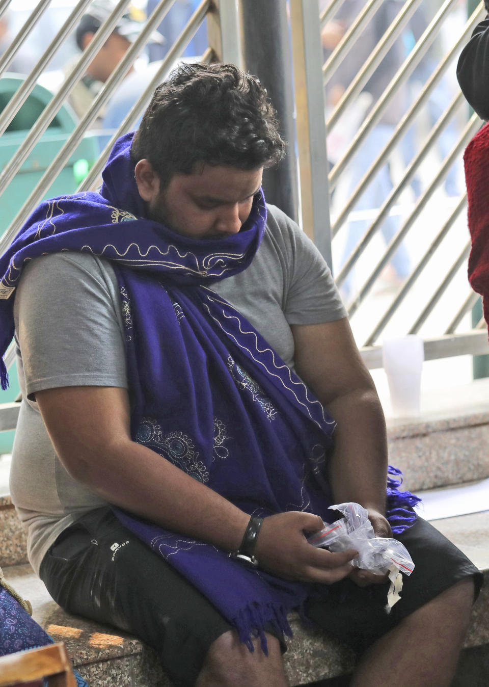 A man holds personal valuables of his relative who died as relatives wait outside a mortuary to receive bodies of those who died in a hotel fire in New Delhi, India, Tuesday, Feb. 12, 2019. A fire engulfed a shoddily built budget hotel in central New Delhi early Tuesday, killing more than a dozen people. (AP Photo/Manish Swarup)