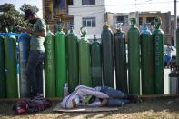 People wait in a line with empty oxygen tanks hoping to refill the canisters for relatives suffering from COVID-19, in Lima, Peru, Friday, Jan. 29, 2021. The Andean country was one of the worst-hit in the region by the new coronavirus pandemic during 2020 and is now experiencing a resurgence in cases. (AP Photo/Rodrigo Abd)