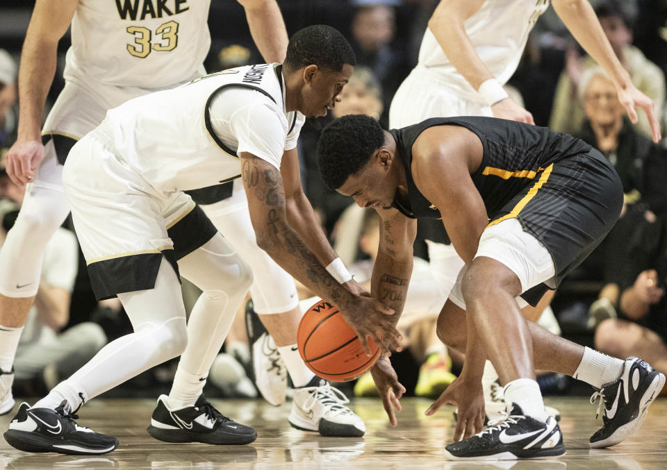 Wake Forest guard Daivien Williamson (4) and Appalachian State forward Donovan Gregory (11) vie for a loose ball in the first half of an NCAA college basketball game on Wednesday, Dec. 14, 2022, at Joel Coliseum in Winston-Salem, N.C. (Allison Lee Isley/The Winston-Salem Journal via AP)