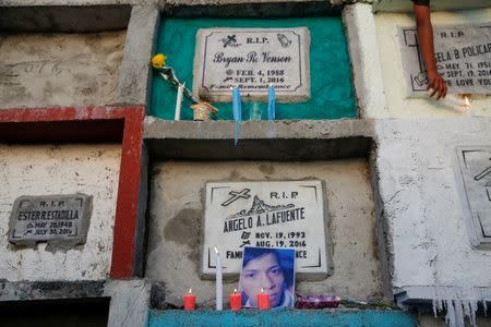 A photograph of Angelo Lafuente, whose body, riddled with bullets, was found by a filthy river that feeds into the Manila bay, is placed with candles on his grave on the All Saints Day in Manila, Philippines November1, 2016. REUTERS/Damir Sagolj REUTERS/Damir Sagolj