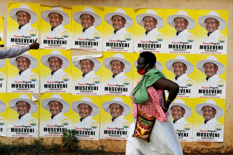 A woman walks past elections posters of Uganda's President Yoweri Museveni on a street in Kampala