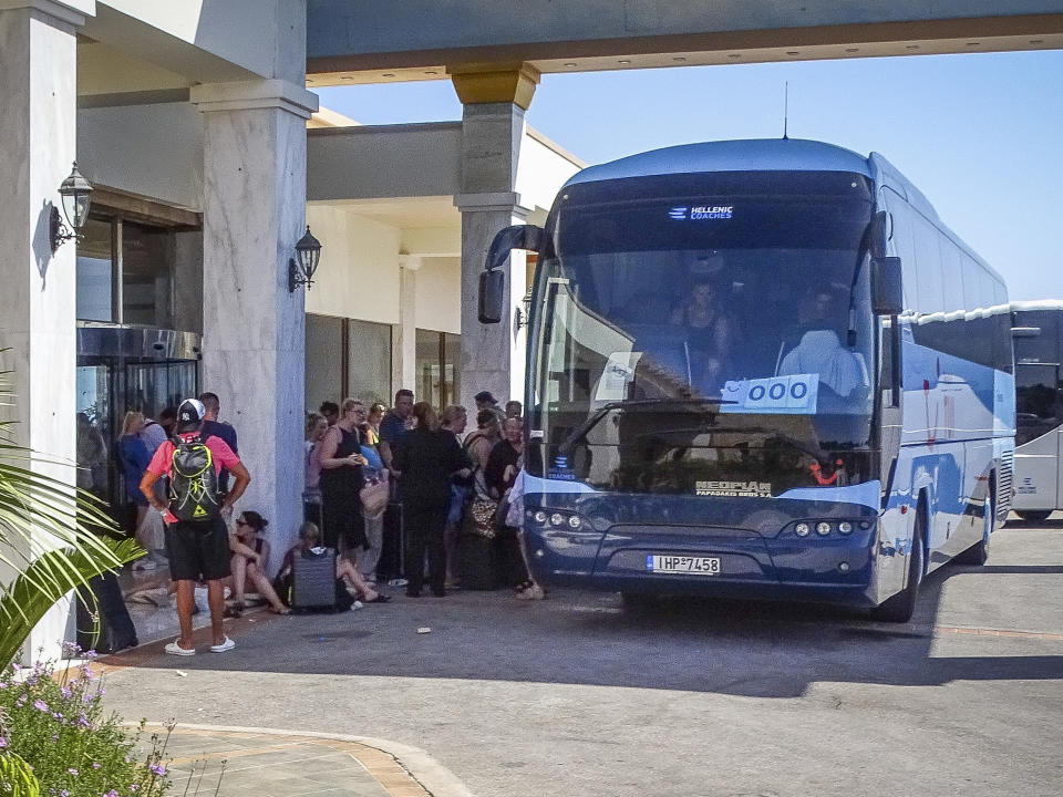 Evacuees wait to board buses as they leave their hotel during a forest fire on the island of Rhodes, Greece, Sunday, July 23, 2023. Some 19,000 people have been evacuated from the Greek island of Rhodes as wildfires continued burning for a sixth day on three fronts, Greek authorities said on Sunday. (Argyris Mantikos/Eurokinissi via AP)