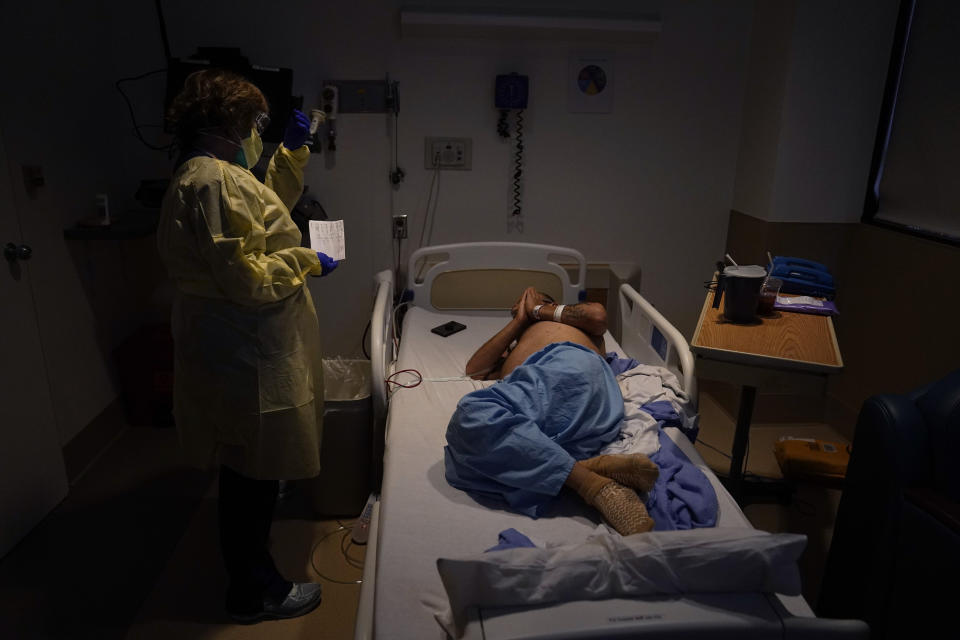 FILE - In this Dec. 22, 2020, file photo, senior chaplain Nancy Many, left, prays with Rafael Lopez in a COVID-19 unit at Providence Holy Cross Medical Center in the Mission Hills section of Los Angeles. California surpassed 25,000 coronavirus deaths since the start of the pandemic, reporting the grim milestone Thursday, Dec. 31, 2020, as it continues to face a surge that has swamped hospitals and pushed nurses and doctors to the breaking point as they brace for an anticipated surge after the holidays. (AP Photo/Jae C. Hong, File)