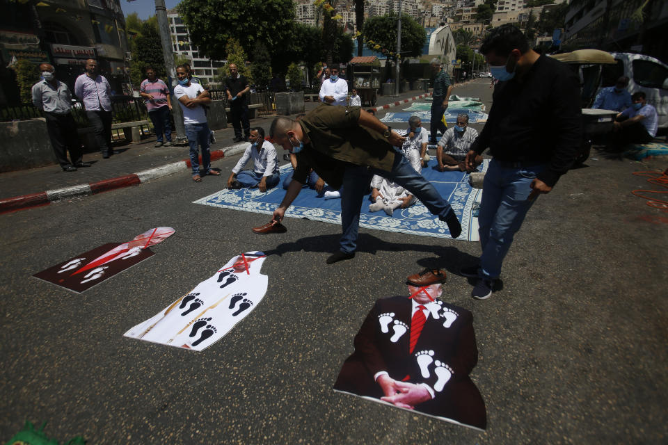 Palestinians Shoes are placed on a pictures of U.S. President Donald Trump, Abu Dhabi Crown Prince Mohammed bin Zayed al-Nahyan and and Israeli Prime Minister Benjamin Netanyahu during a protest against the United Arab Emirates' deal with Israel, in the West Bank city of Nablus, Friday, Aug. 14, 2020.(AP Photo/Majdi Mohammed)