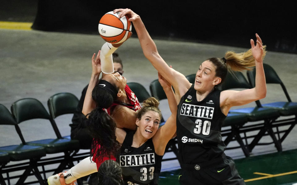 Seattle Storm's Katie Lou Samuelson (33) and Breanna Stewart (30) surround Las Vegas Aces' A'ja Wilson as they vie for the ball in the first half of a WNBA basketball game Saturday, May 15, 2021, in Everett, Wash. The Storm won 97-83. (AP Photo/Elaine Thompson)