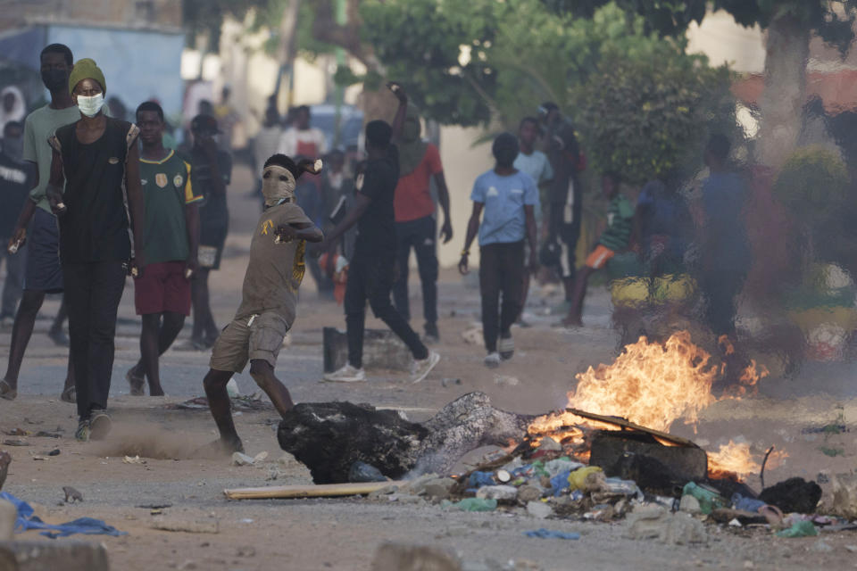 A demonstrator throws a rock at police during a protest at a neighborhood in Dakar, Senegal, Saturday, June 3, 2023. The clashes first broke out later this week after opposition leader Ousmane Sonko was convicted of corrupting youth and sentenced to two years in prison. (AP Photo/Leo Correa)