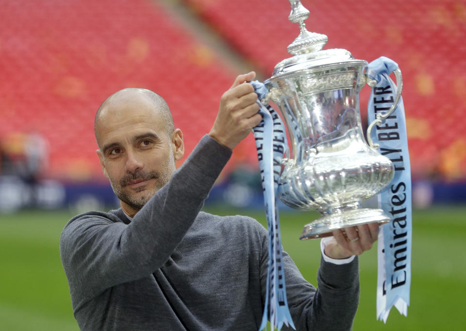 Manchester City's manager Pep Guardiola poses with the trophy after the English FA Cup Final soccer match between Manchester City and Watford at Wembley stadium in London, Saturday, May 18, 2019. (AP Photo/Kirsty Wigglesworth)