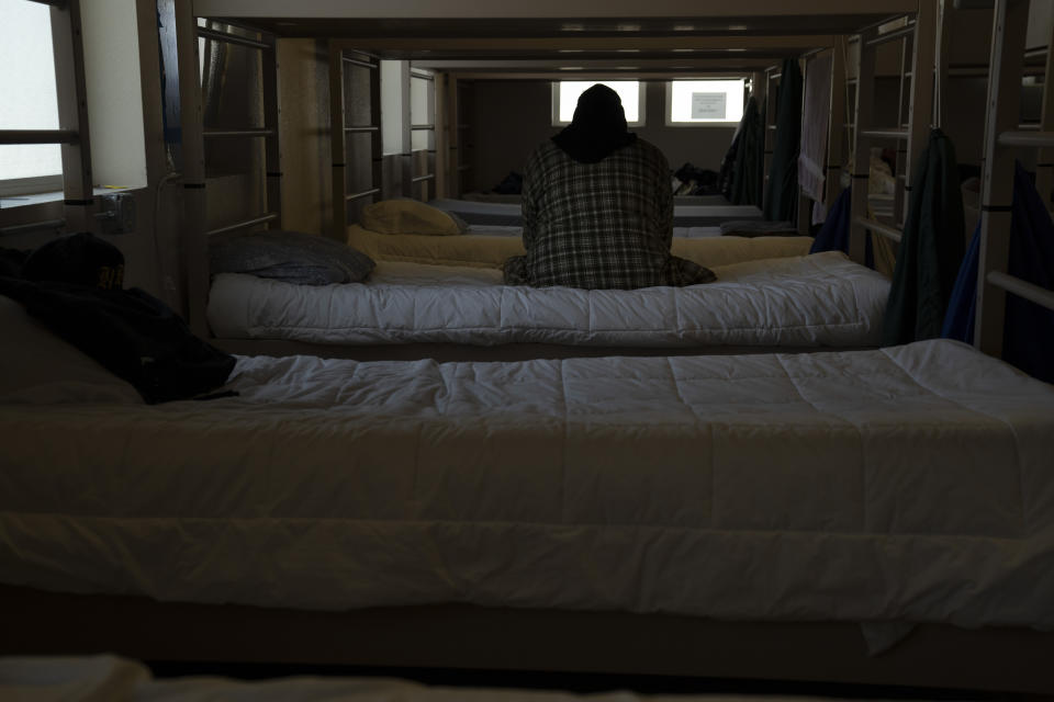 Thomas Person, a resident at the Gospel Rescue Mission, sits on their bed before dinner on Thursday, March 21, 2024, in Grants Pass, Ore. Person arrived at the shelter on March 18. (AP Photo/Jenny Kane)