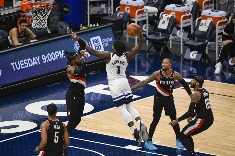 Minnesota Timberwolves guard Anthony Edwards (1) goes up to dunk over Portland Trail Blazers forward Robert Covington as Trail Blazers guard Rodney Hood (5), guard Damian Lillard (0) and  forward Carmelo Anthony (00) look on during the second half of an NBA basketball game Sunday, March 14, 2021, in Minneapolis. (AP Photo/Craig Lassig)