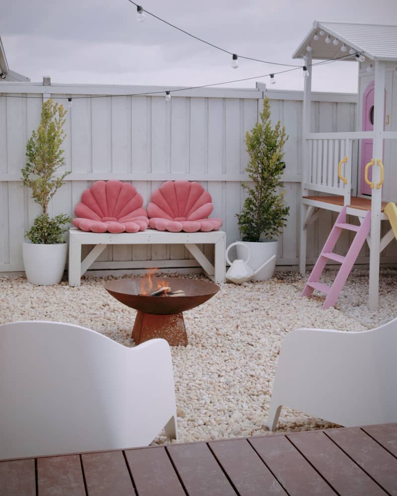 backyard with kids playhouse and bench with scallop shell pillows