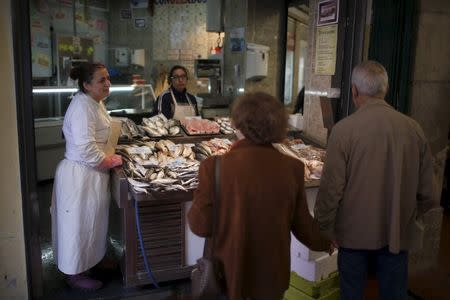 Sonia Silva, 41, speaks with customers at her fish stall in Almada's market, near Lisbon, Portugal November 18, 2015. REUTERS/Rafael Marchante