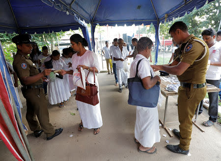 Police officers search the bags of the worshipers at an entrance of the Kelaniya Buddhist temple during Vesak Day, commemorating the birth, enlightenment and death of Buddha, in Colombo, Sri Lanka May 18, 2019. REUTERS/Dinuka Liyanawatte