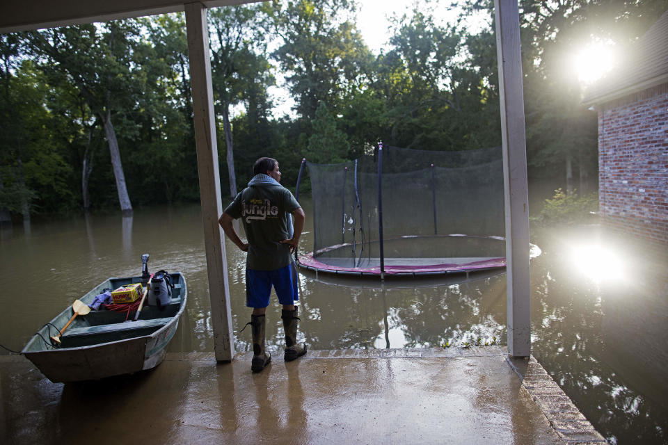 FILE- In this Aug. 16, 2016 file photo, David Key looks at the back yard of his flooded home in Prairieville, La. Memories of an epic flood that caused billions of dollars in damage had Louisiana's capital on edge Friday, July 12, 2019, as Barry gained strength in the Gulf of Mexico. (AP Photo/Max Becherer, File)