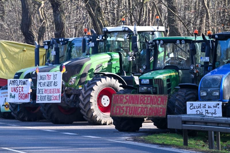 Tractors with banners stand near the entrance to the Oberstufenzentrum (OSZ) Neuruppin before the German Foreign Minister Baerbock's visit. Soeren Stache/dpa