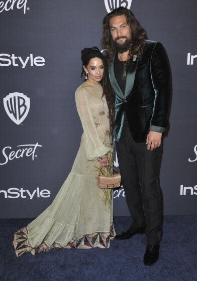 Lisa Bonet, left, wears a light green dress and Jason Momoa, right, wears a green suede jacket, black pants and green shirt