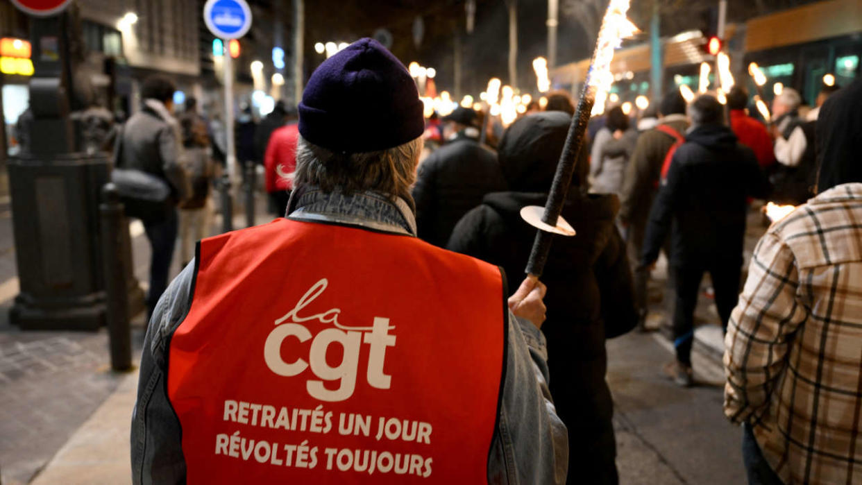 Protesters take part in a torch-lit march called by the CGT workers' union to protest the French government's pensions reform plan, on the Canebiere in Marseille, southeastern France, on January 17, 2023. - France is to face strikes across different sectors on January 19, 2023, as workers join a nationwide strike against a widely unpopular pension reform plan. The suggested changes, still to be debated in parliament, would raise the retirement age from 62 to 64 and increase contributions required for a full pension. (Photo by Nicolas TUCAT / AFP)