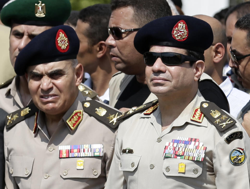 FILE - In this Friday, Sept. 20, 2013 file photo, Egypt's Defense Minister Gen. Abdel-Fattah el-Sissi, center, Egyptian Prime Minister Hazem el-Beblawi, right, and army's Chief of Staff Lt. Gen. Sedki Sobhi, left, attend the funeral of Giza Police Gen. Nabil Farrag in Cairo, Egypt. The head of Egypt’s military, Abdel-Fattah el-Sissi, is riding on a wave of popular fervor that is almost certain to carry him to election as president. Unknown only two years ago, a broad sector of Egyptians now hail him as the nation’s savior after he ousted the Islamists from power, and the state-backed personality cult around him is so eclipsing, it may be difficult to find a candidate to oppose him if he runs. Still, if he becomes president, he faces the tough job of ruling a deeply divided nation that has already turned against two leaders. (AP Photo/Hassan Ammar, File)