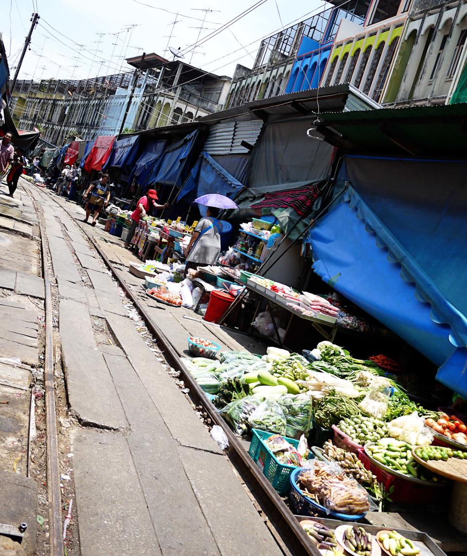 <p>But if you look down on the road, you’ll realise that you’re actually walking on train rails! And when you hear a siren, it’s time to step back into safety and let the action unfold. One moment, locals are shopping for the vegetables; the next they are waiting patiently at the side while stall keepers are scooping up their baskets and boxes of goods with a rather lackadaisical attitude about the whole exercise. Tourists are of course the most excited as they set up their cameras so they don’t miss the action.</p>