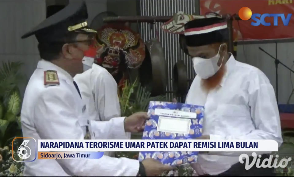 In this image made from SCTV video shot on Wednesday, Aug. 17, 2022, convicted Muslim militant Umar Patek, right, receives his sentence reduction letter during a ceremony at Porong Prison in Sidoarjo, Central Java, Indonesia. Australia's leader said Friday that it's upsetting Indonesia has further reduced the prison sentence of the bombmaker in the Bali terror attack that killed 202 people, which could free him within days if he's granted parole. (AP Photo)