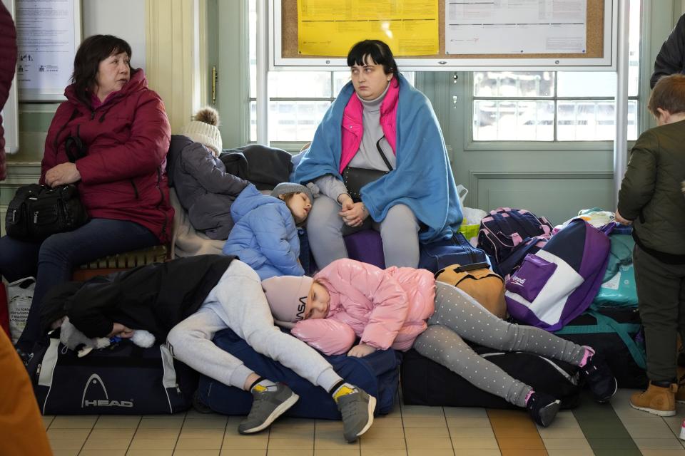 Ukrainians, including children who are are sprawled out to rest, inside a train station.