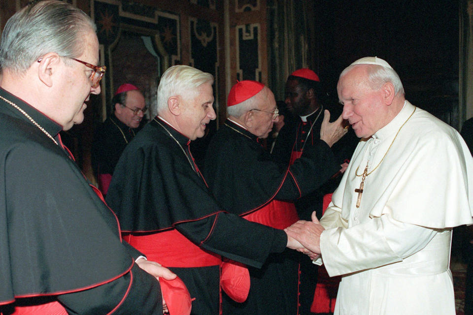 FILE - Pope John Paul II shakes hands with Cardinal Joseph Ratzinger, head of the Congregation for the Doctrine of the Faith, during the ceremony of the Christmas greetings at the Vatican on Dec. 22, 1995. At left is Vatican Secretary of State Cardinal Angelo Sodano and third from left, waving, is former Vatican Secretary of State Cardinal Agostino Casaroli. As John Paul’s right-hand man on doctrinal matters, Ratzinger wrote documents reinforcing church teaching opposing homosexuality, abortion and euthanasia, and asserting that salvation can only be found in the Catholic Church. Benedict, the German theologian who will be remembered as the first pope in 600 years to resign, has died, the Vatican announced Saturday Dec. 31, 2022. He was 95. (AP Photo/Massimo Sambucetti, File)