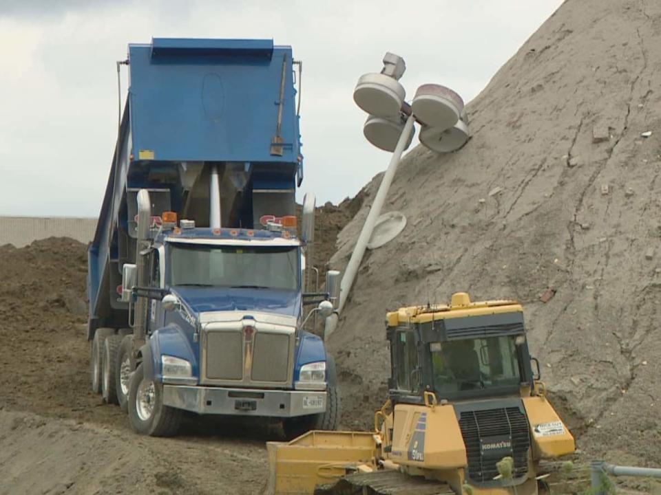 Davenport resident Noelle Pittock wants the City of Toronto to explain why these large dirt mounds have taken over the vacant flea market lot by her house. (Paul Borkwood/CBC - image credit)