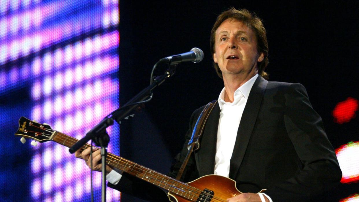 Paul McCartney playing guitar on stage