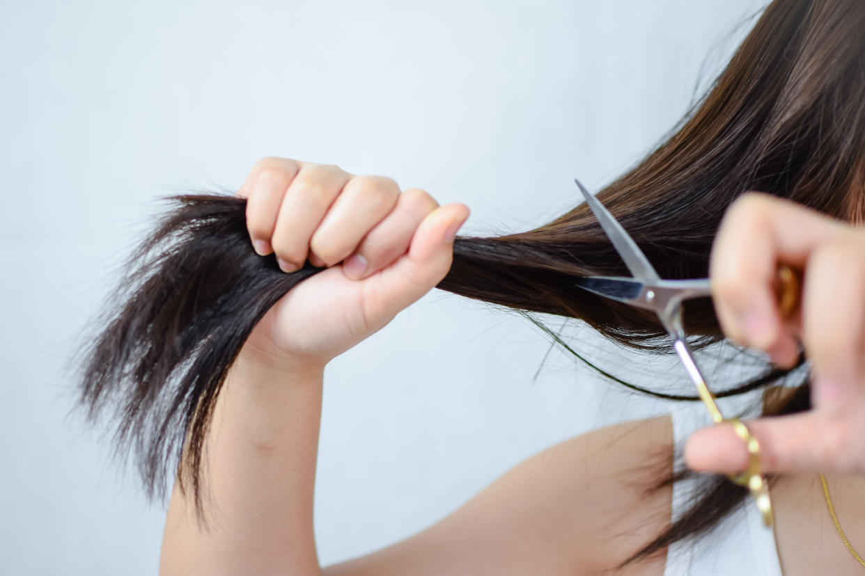 Midsection Of Woman Cutting Hair Against White Background