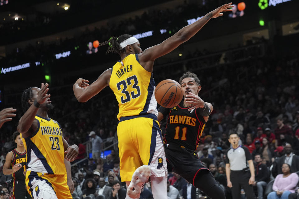 Atlanta Hawks guard Trae Young (11) passes around Indiana Pacers center Myles Turner (33) during the first half of an NBA basketball game Friday, Jan. 12, 2024, in Atlanta. (AP Photo/John Bazemore)