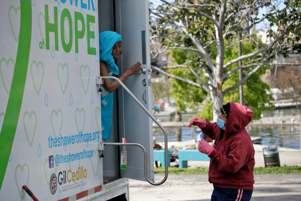 Lisa Marie Nava, right, helps a woman taking a shower at a mobile service for the homeless provided by The Shower of Hope MacArthur Park Monday, March 23, 2020, in Los Angeles. California residents have been told to keep away from others, not gather in groups and wash their hands frequently due to threat posed by the coronavirus.