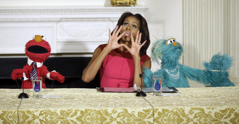First lady Michelle Obama, center, with PBS Sesame Street's characters Elmo, left, and Rosita, right, to help promote fresh fruit and vegetable consumption to kids in an event in the State Dining Room of the White House in Washington, Wednesday, Oct. 30, 2013. Sesame Workshop and the Produce Marketing Association (PMA) joined in Partnership for a Healthier America (PHA) in announcing a 2-year agreement to making healthy choices by using the Sesame Street characters to help deliver the messages about fresh fruits and vegetables. (AP Photo/Pablo Martinez Monsivais)
