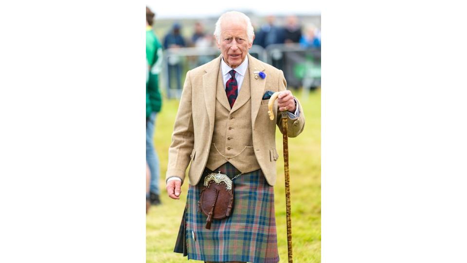 King Charles in a tan coat and kilt