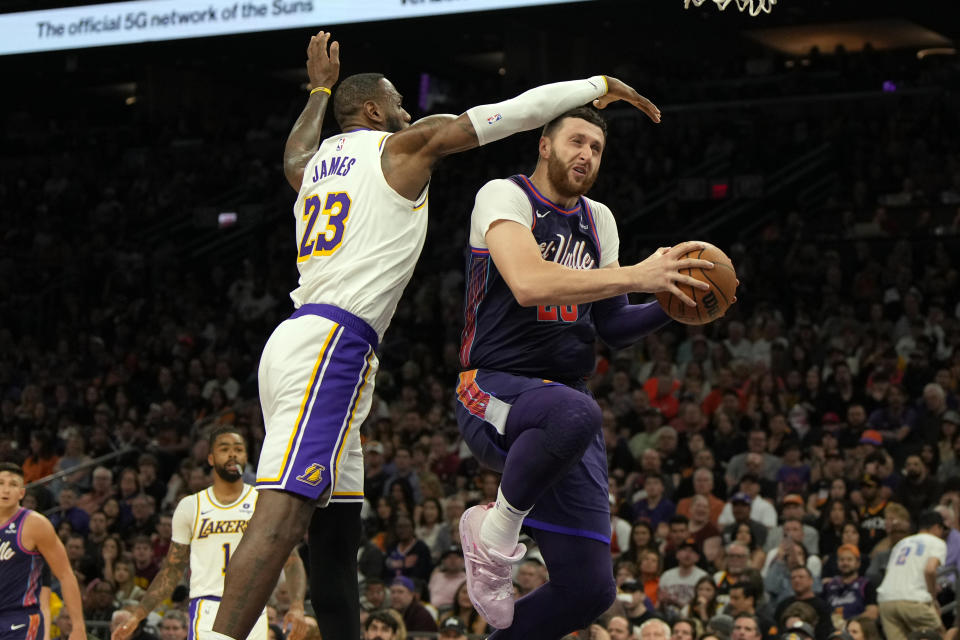 Los Angeles Lakers forward LeBron James (23) fouls Phoenix Suns center Jusuf Nurkic, right, during the second half of an NBA basketball game, Sunday, Feb. 25, 2024, in Phoenix. (AP Photo/Rick Scuteri)