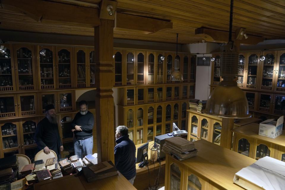 Father Theofilos, a Pantokrator monk, left, Byzantine scholar Yiannis Niehoff-Panagiotidis, center, and Anastasios Nikopoulos, a jurist and scientific collaborator of the Free University of Berlin, speak each other at the library of Pantokrator Monastery in the Mount Athos, northern Greece, on Thursday, Oct. 13, 2022. Deep inside a medieval fortified monastery in the Mount Athos monastic community, researchers are for the first time tapping a virtually unknown treasure: thousands of Ottoman-era manuscripts that include the oldest of their kind in the world. (AP Photo/Thanassis Stavrakis)