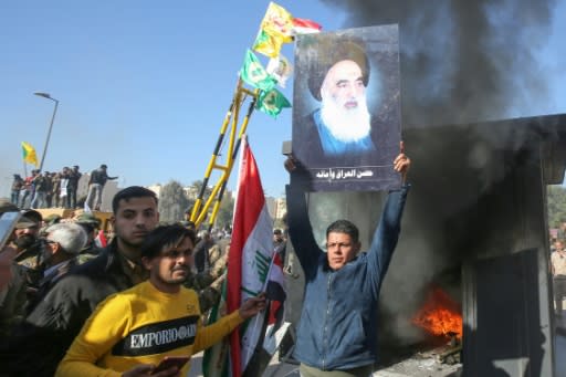 An Iraqi supporter of the Hashed al-Shaabi paramilitary network lifts a picture of Iraq's top Shiite cleric Grand Ayatollah Ali Sistani in front of the US embassy in Baghdad