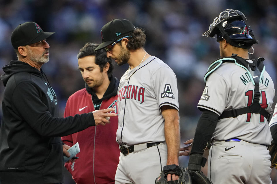 Arizona Diamondbacks manager Torey Lovullo, left, talks with starting pitcher Zac Gallen, who leaves the game with an injury, while catcher Gabriel Moreno, right, watches during the sixth inning of the team's baseball game against the Seattle Mariners, Friday, April 26, 2024, in Seattle. (AP Photo/Lindsey Wasson)