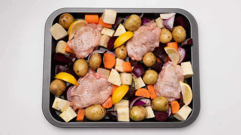 uncooked chicken and vegetables on sheet pan